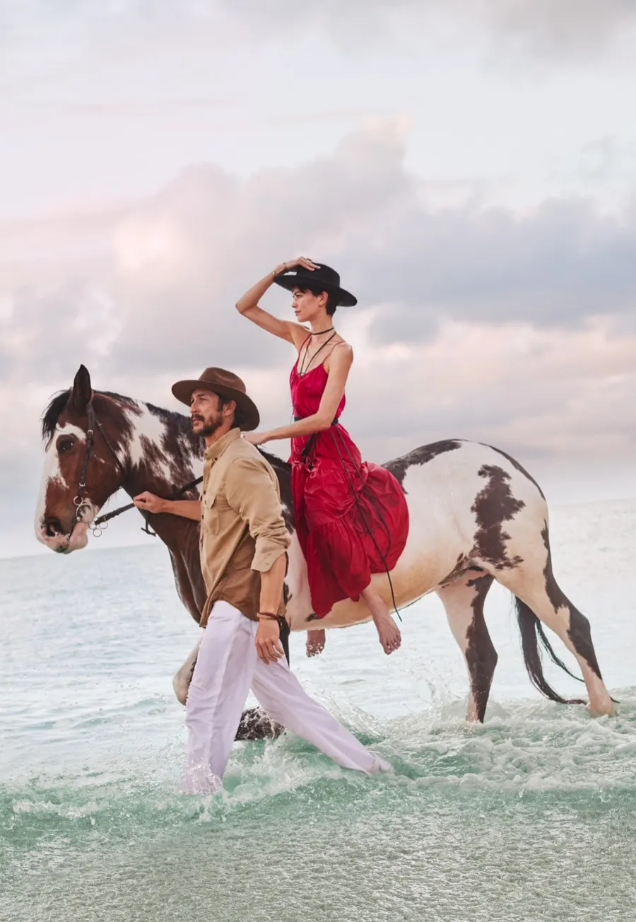 Model in a red dress on horseback in the shallows