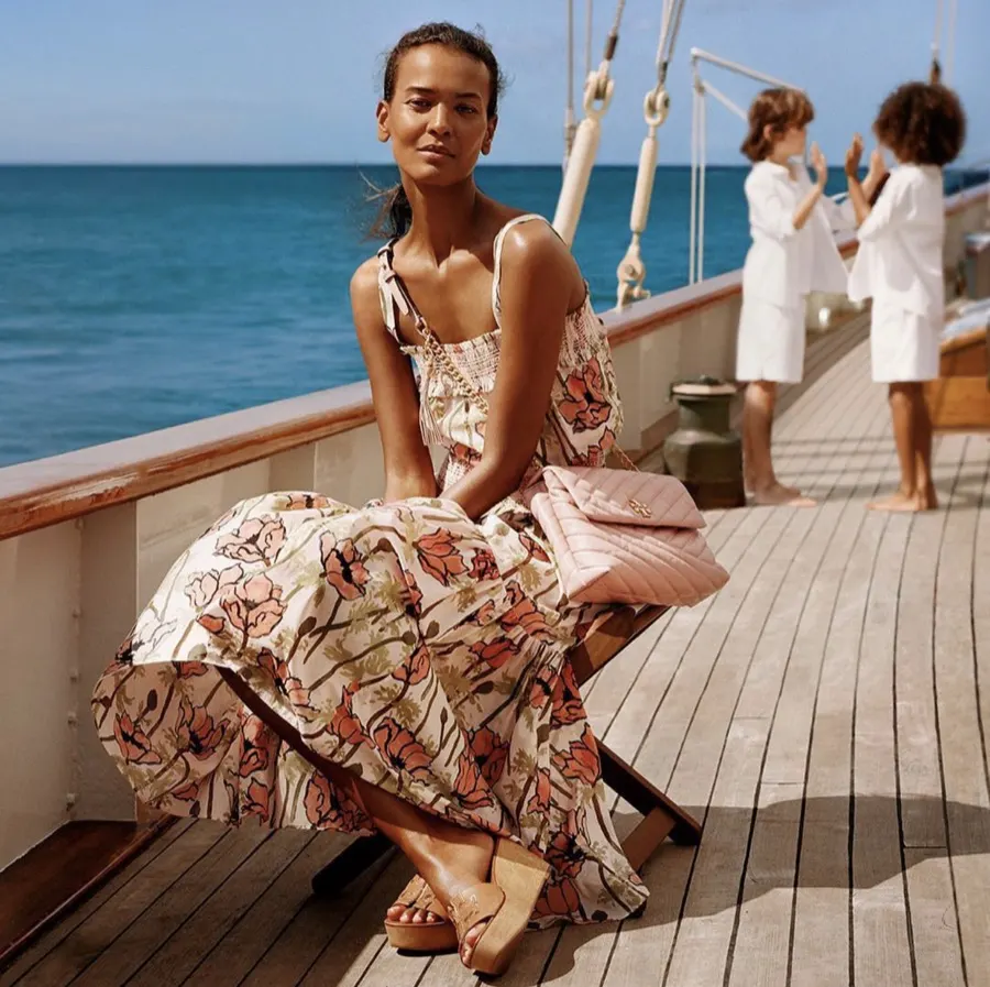 Model in a printed dress on a teak deck